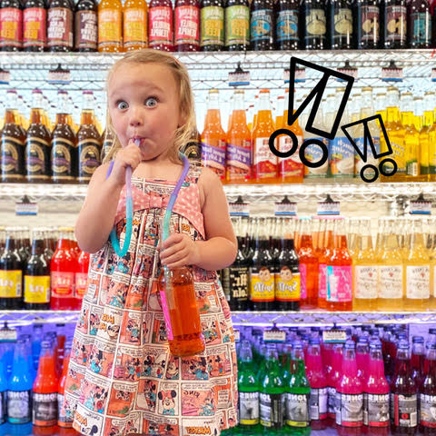 Kid standing in front of the drink aisle sipping on a drink using silicone straws attached to each other