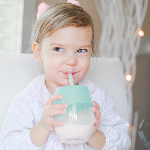Toddles holding a glass with a stretchy silicone lid and straw