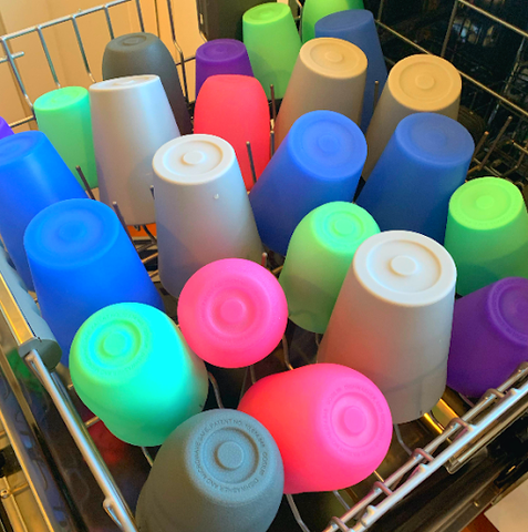 A bunch of different reusable silicone cups placed in the top rack of the dishwasher