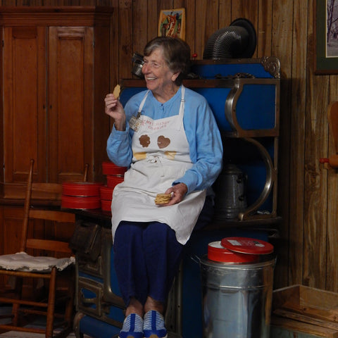 Mrs. Hanes' posing with cookies next to an antique wood stove.
