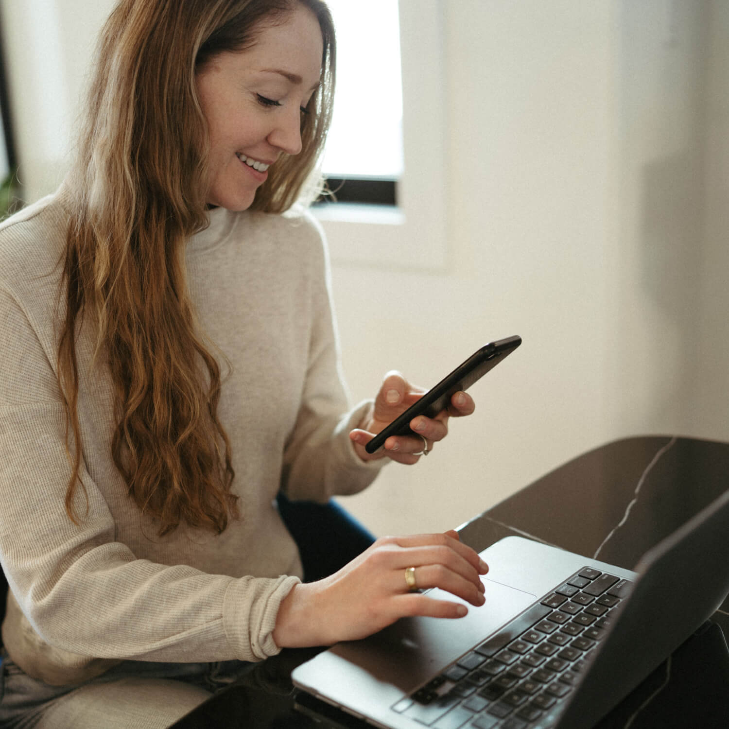 owner Sherah shown smiling with her laptop and phone, sending out an email to subscribers
