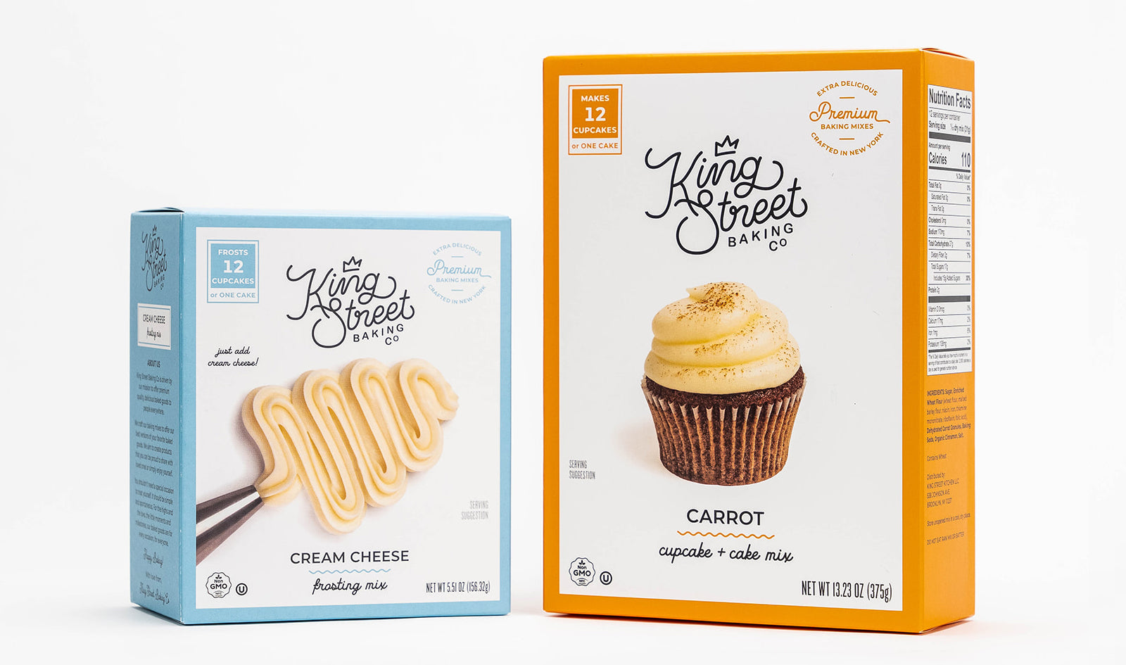 One light blue box of King Street Baking Co.'s Cream Cheese Frosting Mix next to one orange box of King Street Baking Co.'s Carrot Cake and Cupcake Mix.