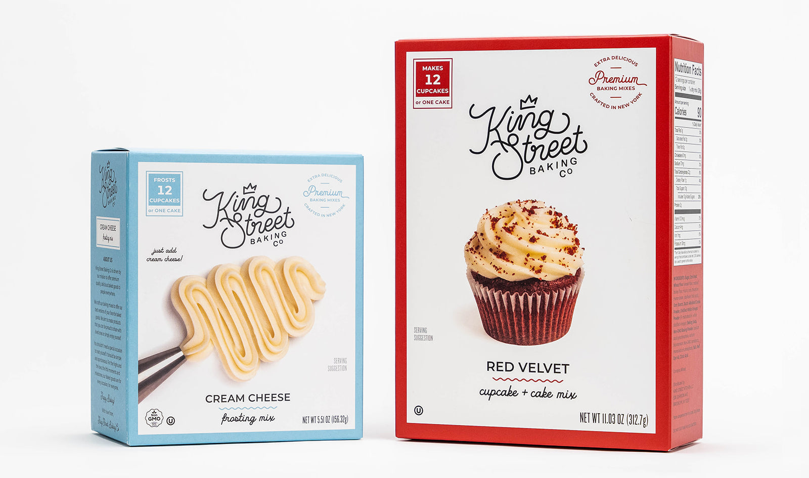 One light blue box of King Street Baking Co.'s Cream Cheese Frosting Mix (left) next to a red box of King Street Baking Co.'s Red Velvet Cupcake and Cake Mix