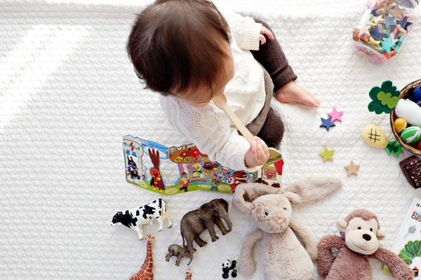 Baby mit Spielzeug sitzt auf Decke