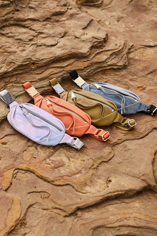 Several Aimee Kestenberg Milan Belt Bags sitting on a rock formation