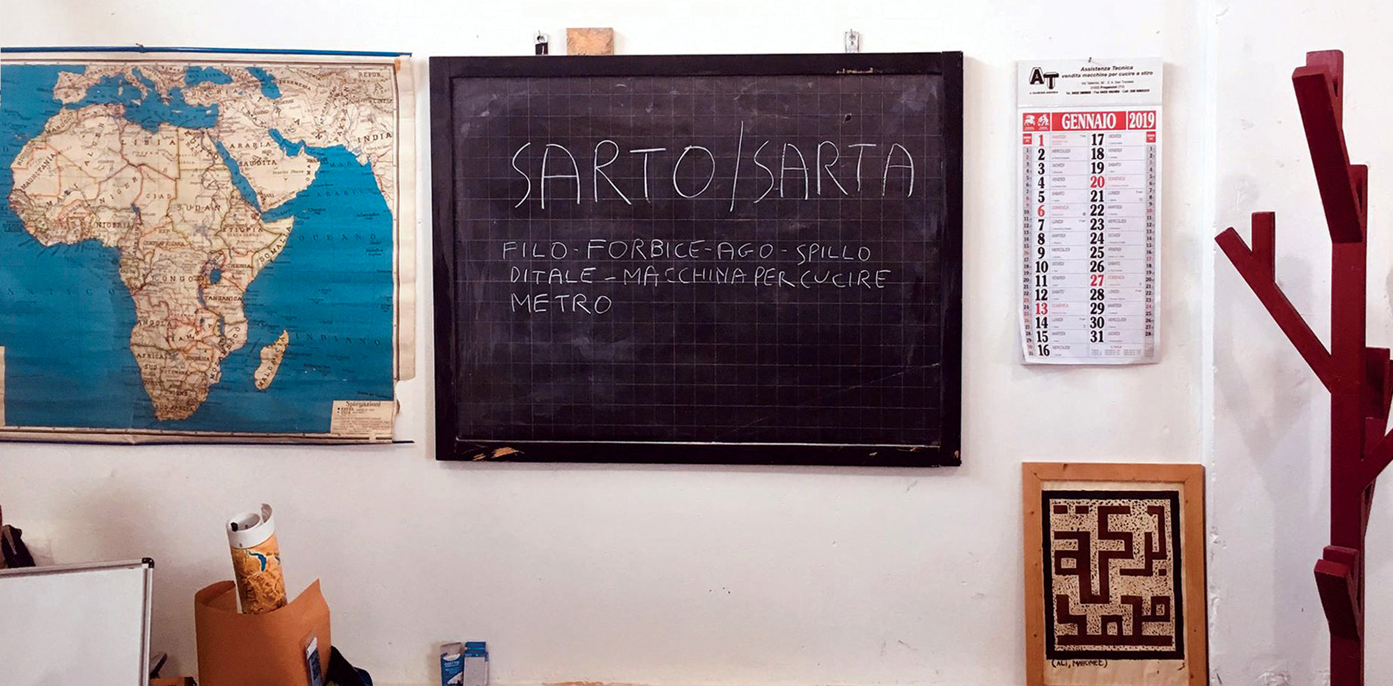Lavagna con su scritto Sarto / Sarta accanto a mappa dell'Africa in classe