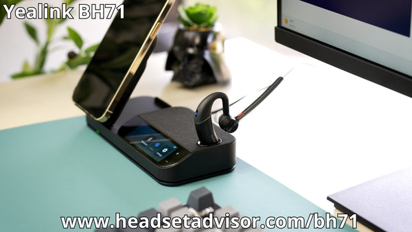 Yealink BH71 resting in charging cradle, showing a mobile phone upright in resting in the wireless charger, all sittinng on an office desk