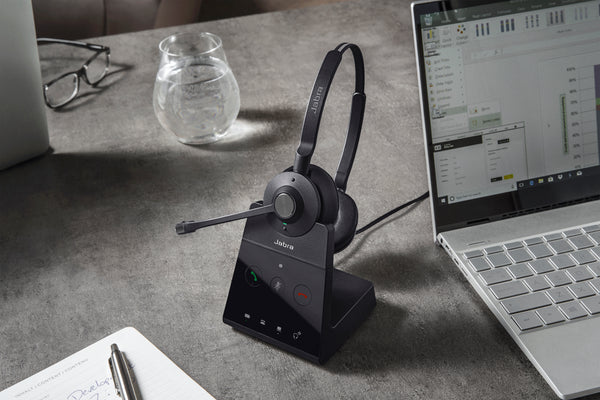 Jabra engage 65 wireless headset in the charging base on the desk top.