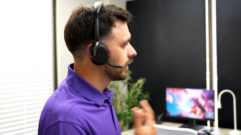 image of a man wearing a Jabra Evolve2 65 Flex headset while on a business call and sitting at an office desk.