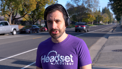 Man with purple Headset Advisor shirt walking down a busy street wearing a Jabra Evolve2 65 Flex headset