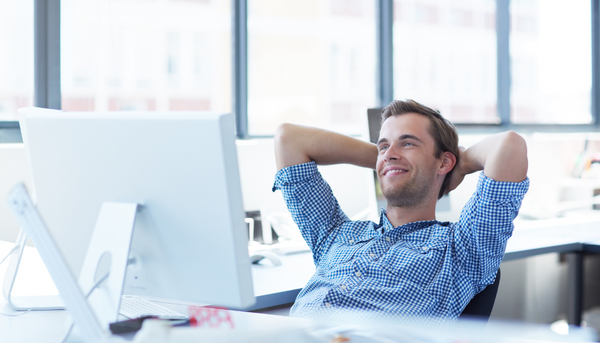 Man behind desk with arms behind head looking relaxed