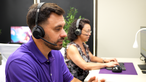 man in foreground wearing Evolve2 55 headset on a call with a woman on a call in the background