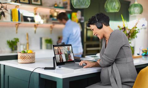 Woman sitting at an office desk wearing a headset while on a multi-person video call