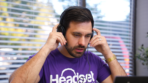 Man in office wearing a Headset Advisor purple  shirt taking off his double ear headset