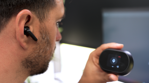man wearing a Poly Voyager Free 60 earbud looking at the screen on the charging case