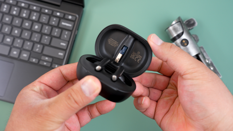 image of man  holding the Poly Voyager Free 60 earbuds case open showing the earbuds, and stored USB adapter