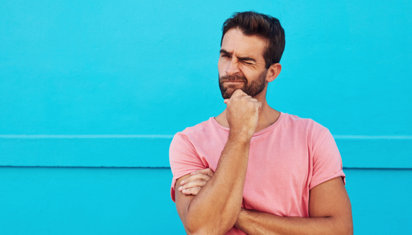 Man in pink shirt with sky blue background, pondering if something is right or not