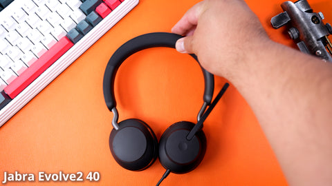 man's arm placing a Jabra Evolve2 40 wired USB headset onto a desk top.