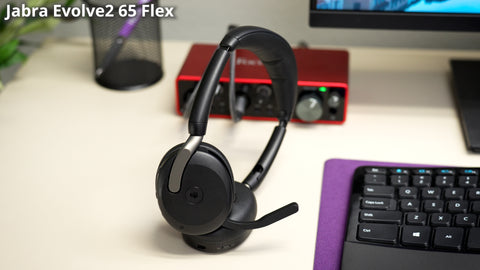 Image of a Jabra Evolve2 65 Flex bluetooth headset sitting on a desk next to a computer