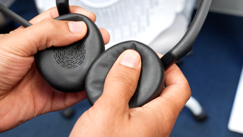 A man's hands shown squeezing inwards the ear cushions on a Jabra headset to show how soft they are