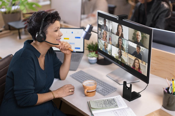 profile of a woman sitting at an office desk wearing a Jabra Evolve2 55 headset while looking at a computer screen