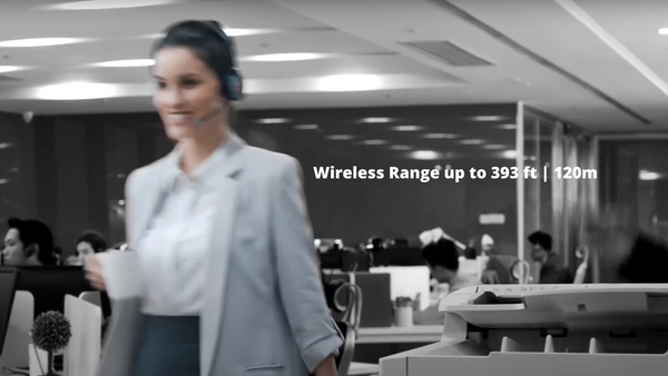 woman wearing a Yealink wireless headset walking through an open office area with text stating up to 393 feet of wireless range