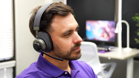 man sitting at desk wearing an Orosound Tilde Pro wireless headset with mic boom