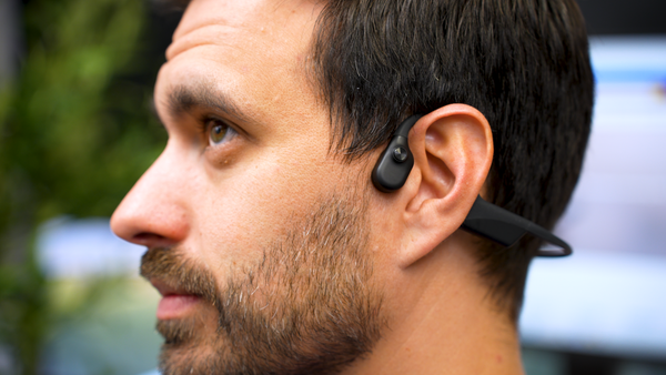 Profile of a Man wearing a Shokz Opencomm2 UC wireless headset outdoors