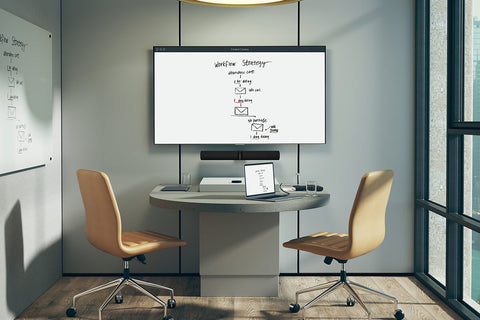 Monitor on wall with office desk and laptop showing shared content on display