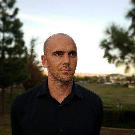 A bald man posed against the dusk sky