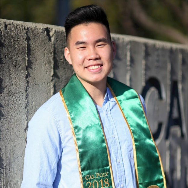 a man in a blue shirt with a green university sash on his shoulders smiling at the camera