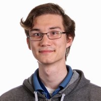 a man with glasses and curl hair looking bemused at the camera