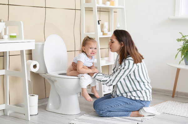 mulher ensinando seu bebê a usar penico no banheiro