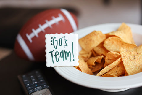 Simple Scallop mini with "go team!" written on it. Chips in bowl and football in background.