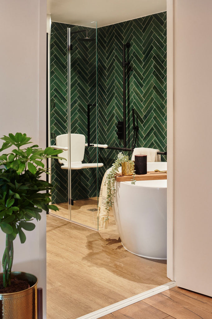  View through a door to a rich green metro tiled wetroom in herringbone style and wood-effect floor tile