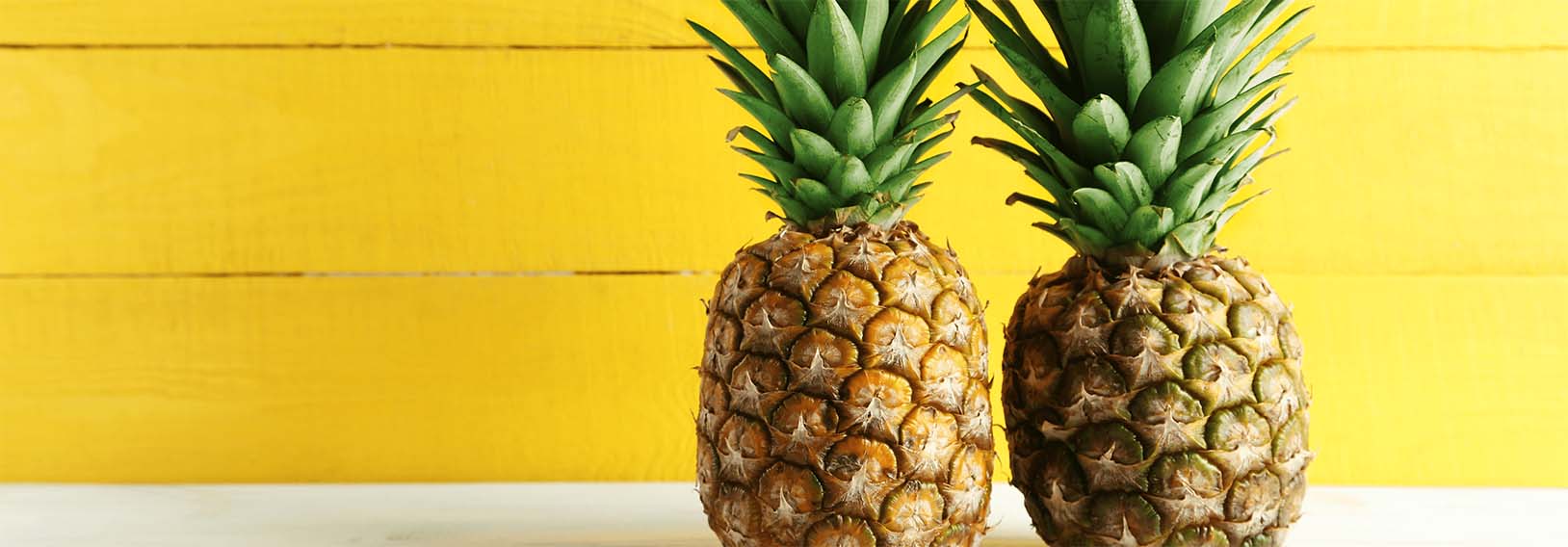 Pineapples in front of yellow wall