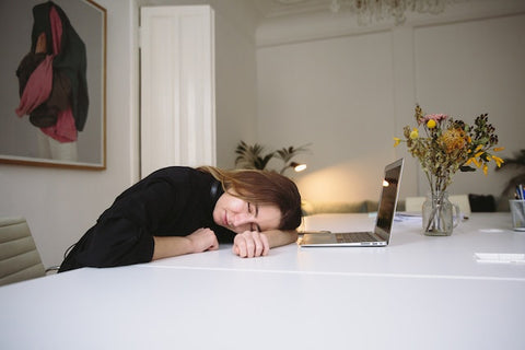 lady napping with her head on desk next to laptop