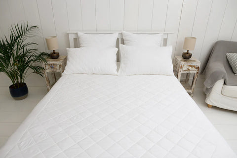 white bed with two pillows and mattress topper