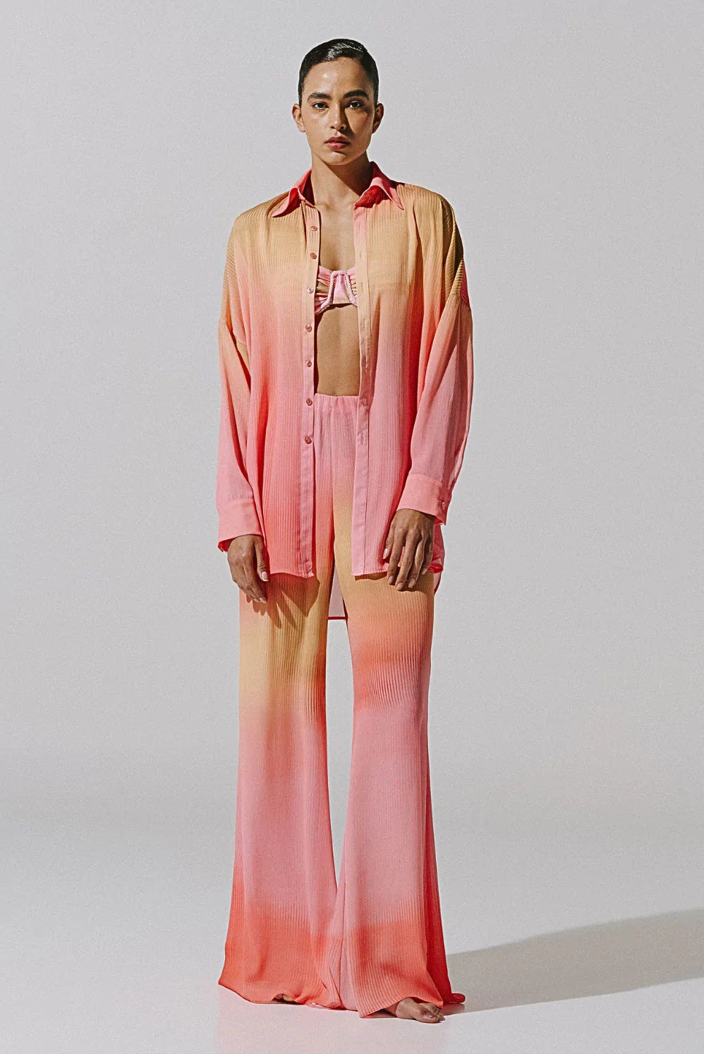 Model in a pink-and-orange ombré matching set featuring a bikini top, open button-down shirt, and wide-leg pants — Matching Sets.