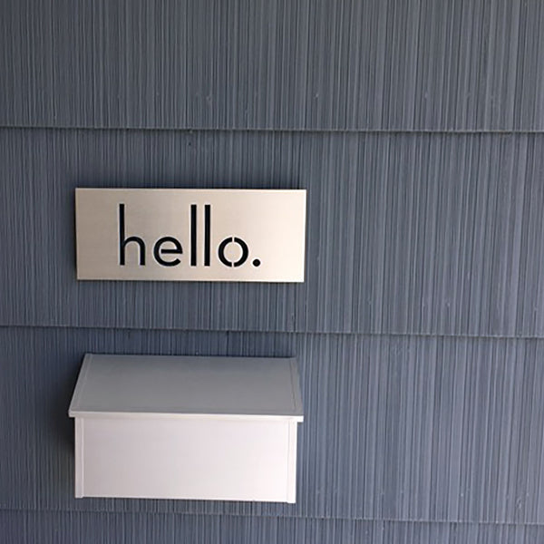Palm Springs 'hello.' plaque in Brushed Aluminum, installed on gray siding above an aluminum modern mailbox - Modern House Numbers"