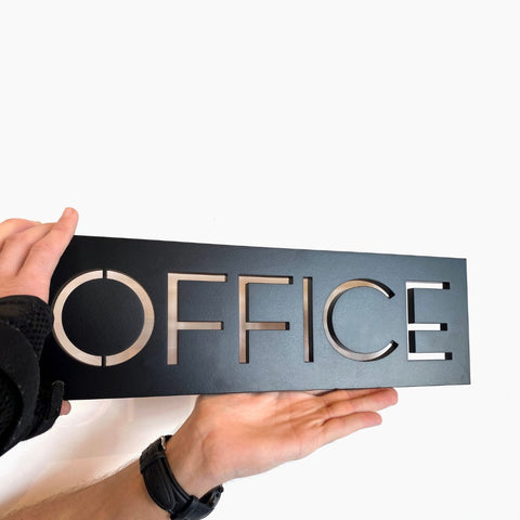 Hands holding "Office" plaque in matte black.