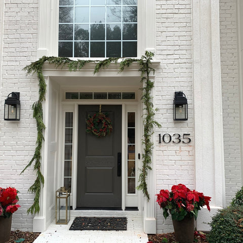 6" matte black, Santa Barbara font '1035' on white painted brick. Holiday garland around front door and poinsettias in foreground.