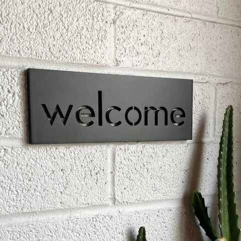 Dark bronze 4" x11" plaque against white exterior brick.