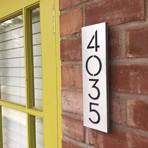 Modern House Numbers 4x11 Vertical Plaque, Brushed Aluminum finish, installed on a red brick wall.