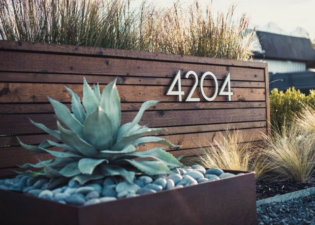 Palm Springs numbers '4204' in Brushed Aluminum installed on a low, modern wood site wall - Modern House Numbers
