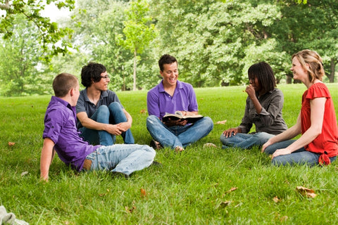 five culturally diverse people reading the bible in a park