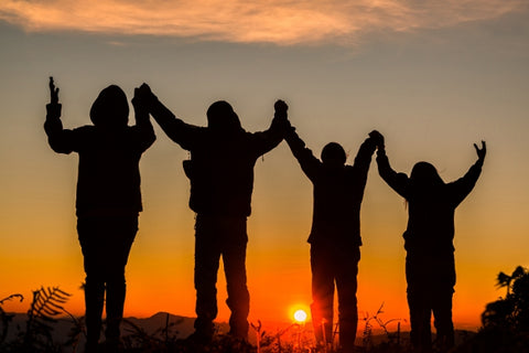 silhouette of group of young people praying at sunset