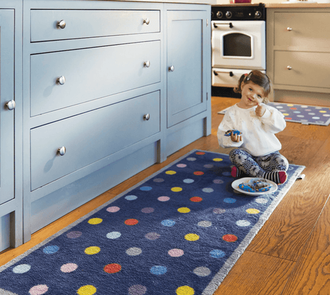 Young girl eating cupcakes on a bright spotted kitchen mat