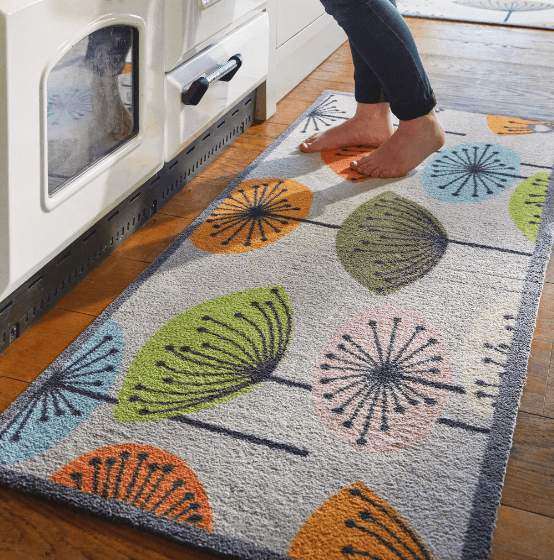 Someone stood on a floral kitchen runner in front of an aga oven