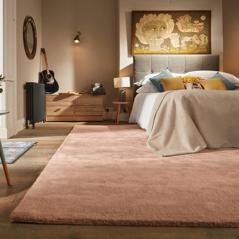 A bedroom featuring a large coral pink wool rug underneath the bed